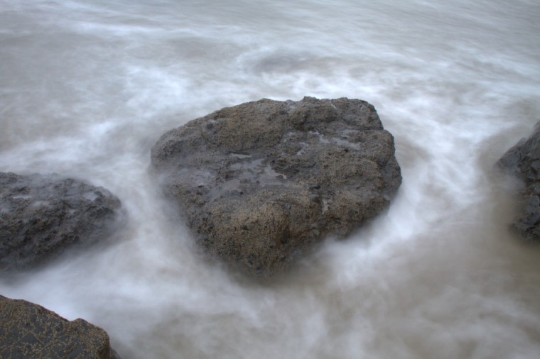 Ocean fog circles around a rock in Canon Beach